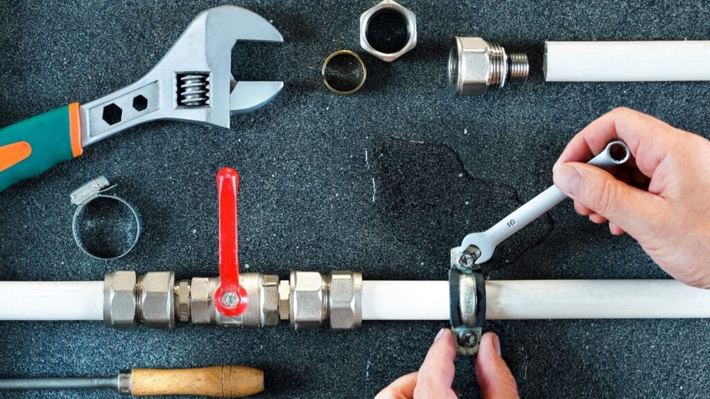 Plumber repairing a pipe valve with an adjustable wrench in Murray