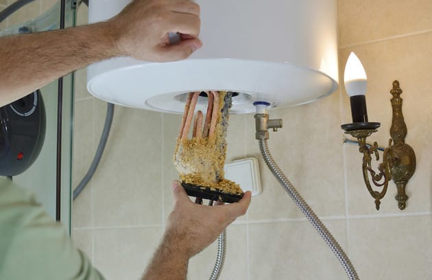 Technician removing mineral buildup from a water heater in Murray