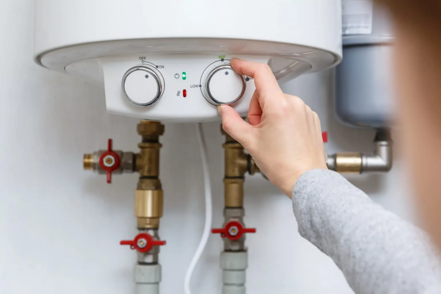 Homeowner adjusting the temperature controls on a water heater in Murray